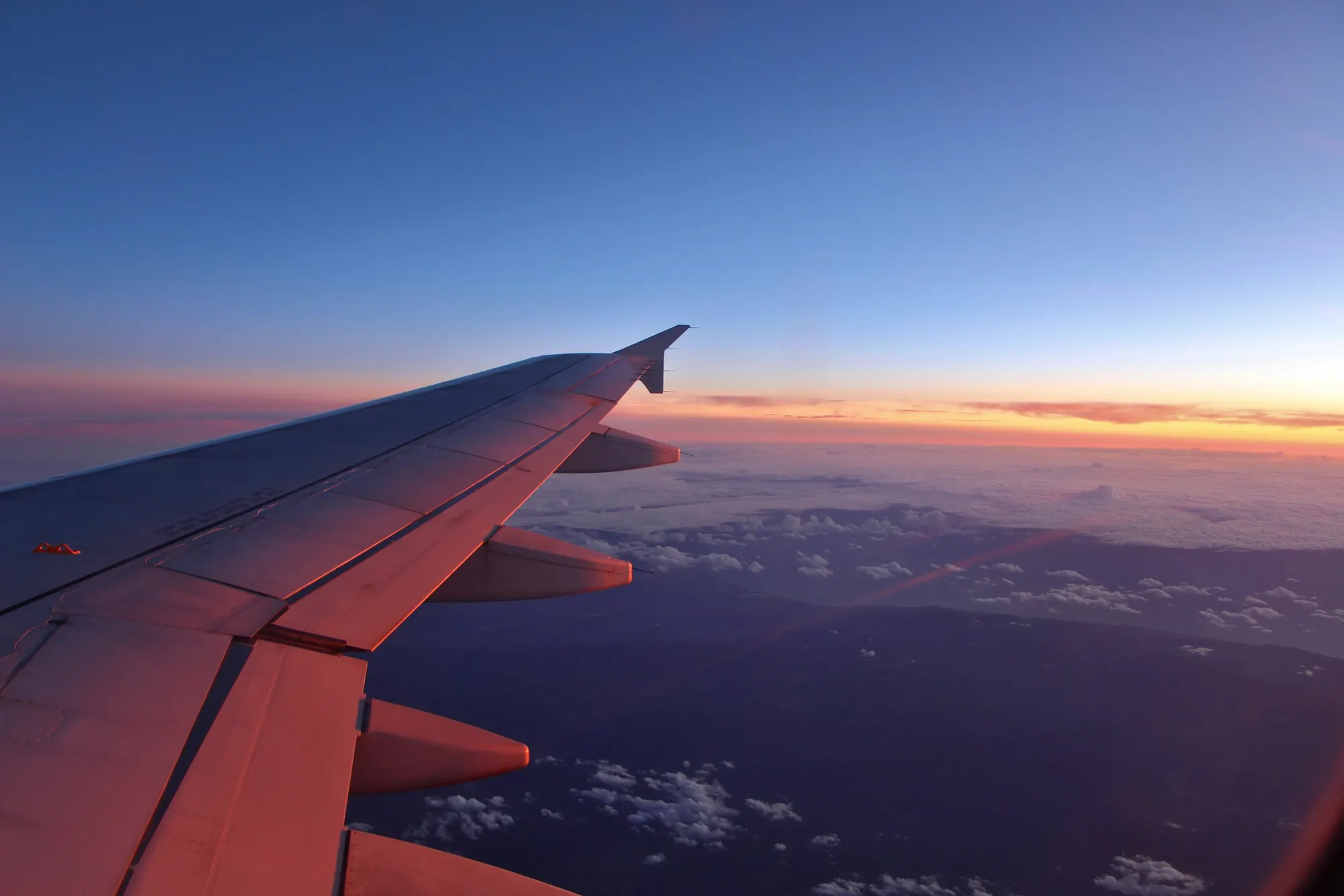 A plane's wing over mountains at dusk