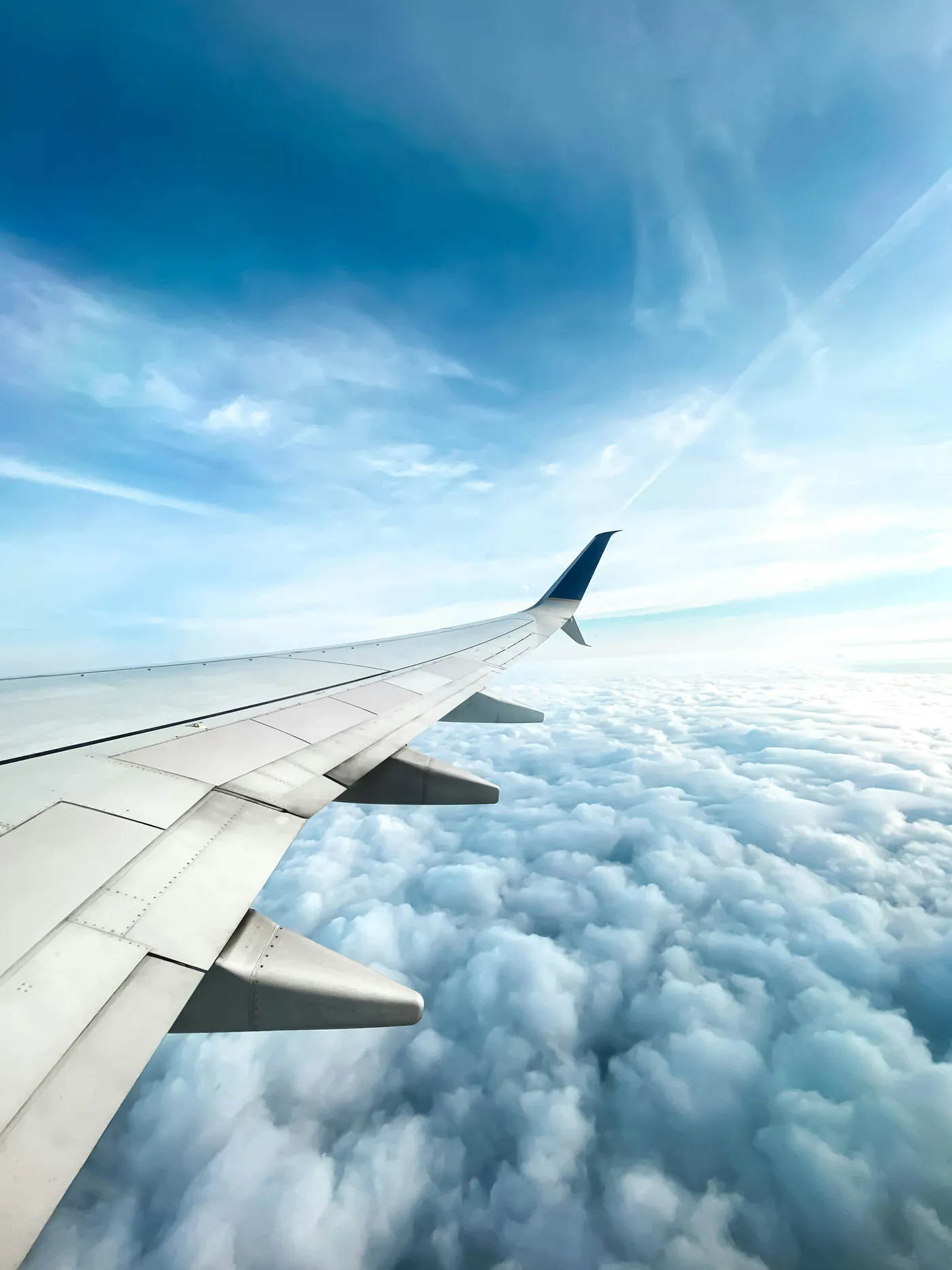 A plane's wing above a sea of clouds, seen from a window seat